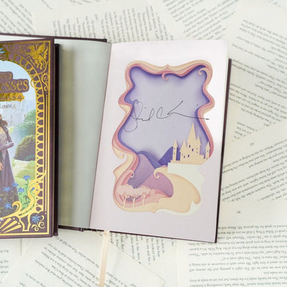 Open book 'The Two Princesses of Bamarre' with a decorative page featuring a castle illustration with the authors signature Gail Carson Levine