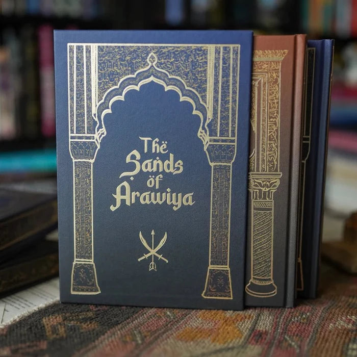 The Sands of Arawiya special edition book with blue and gold foil arch cover design, part of We Hunt the Flame box set