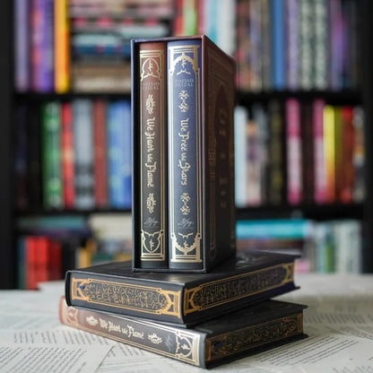 We Hunt the Flame and We Free the Stars special edition book spines stacked on gold-foil hardcover box sets with bookshelf backdrop