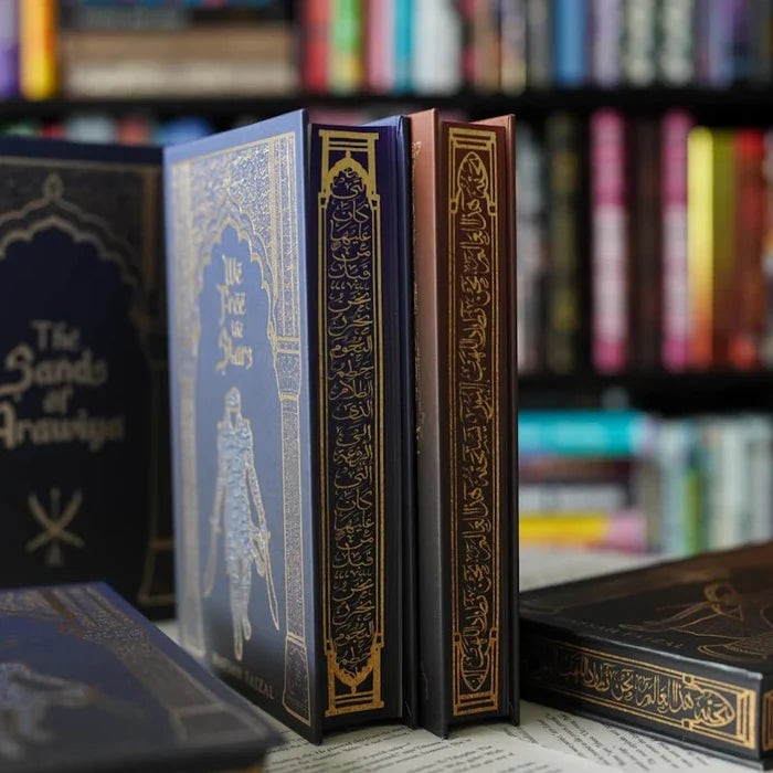 We Hunt the Flame special edition book spines including The Sands of Arawiya standing upright with gold-foil ornate designs