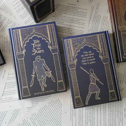 We Free the Stars front and back book covers by Hafsah Faizal with gold-foil character illustrations on navy blue hardcover