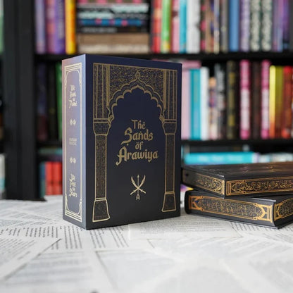 The Sands of Arawiya special edition box standing beside stacked We Hunt the Flame book sets with bookshelf backdrop